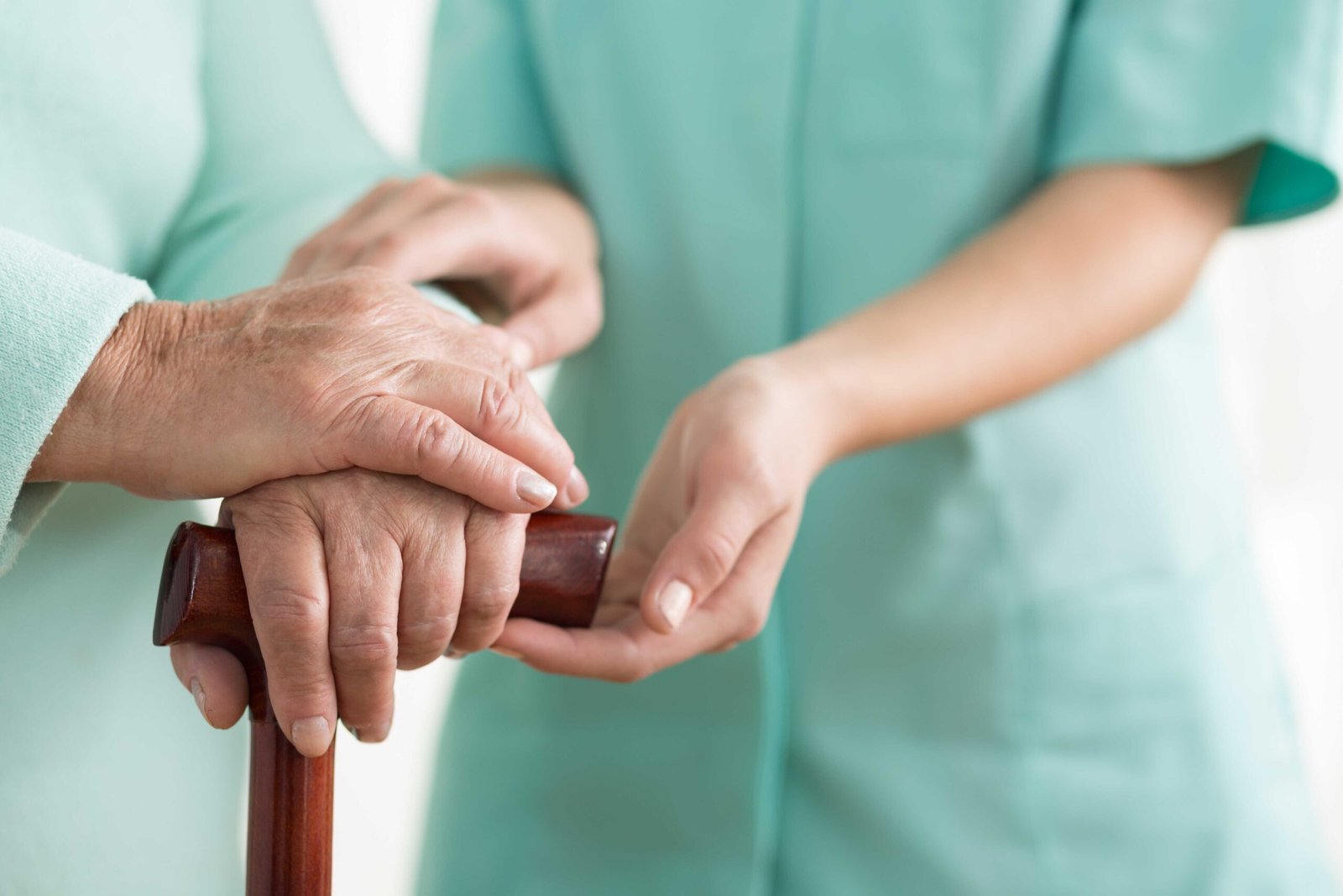 Close-up of woman using cane assisted by physiotherapist